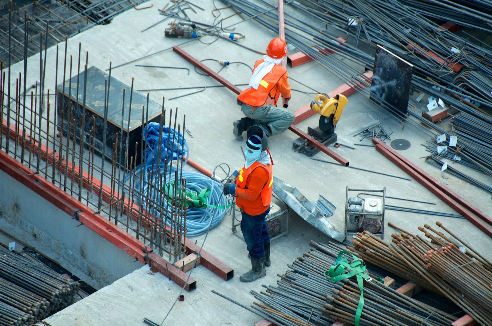 Site workers in orange hi-vis vests laying reinforcement bar