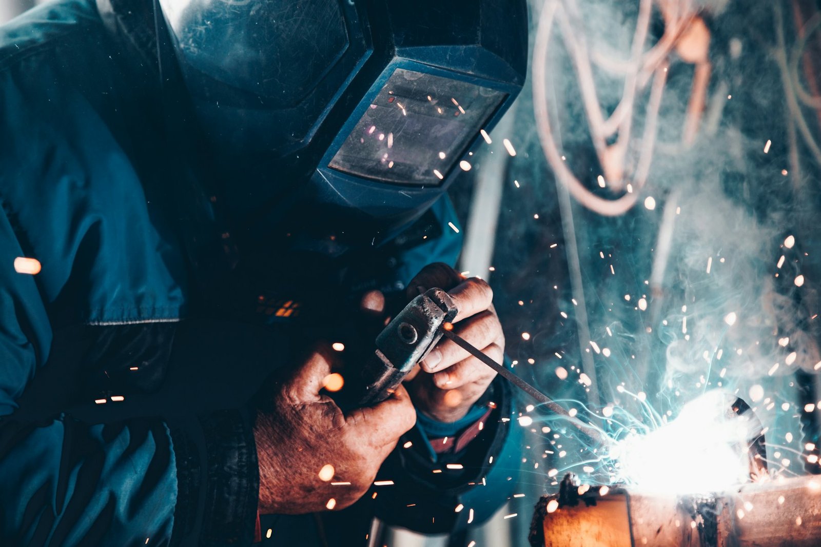 Welder in protective mask joining steel, sparks flying